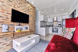 a living room with a red couch and a brick wall at Clear Skies in Kempton Park
