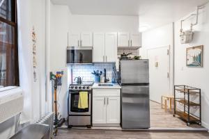 a kitchen with white cabinets and a stainless steel refrigerator at Oasis Apartment by Columbus Circle & Times Square in Manhattan in New York +3 photos