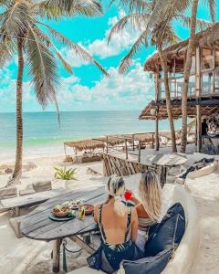 two women sitting on a picnic table on the beach at Jungle Guardian - Rooftop Pool & Beach Club in Zona Hotelera Tulum in Tulum +110 photos