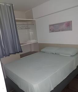 a small bedroom with a bed with white sheets at Flat Grand Praia de Iracema in Fortaleza