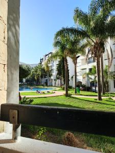 a park with palm trees and a swimming pool at L'Olivier à Marina Golf Vue sur Piscine, Wi-Fi et Clim in Asilah