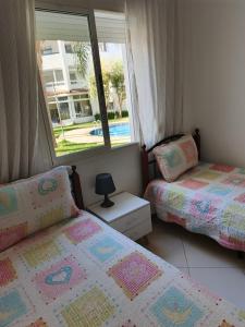 two beds in a room with a window at Olivier Asilah Golf Piscines in Asilah