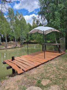 a wooden dock with a gazebo on a lake at Domki Bartoszówka 