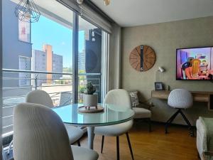 a living room with a table and chairs and a clock at Like a Home - 2Bedrooms - QueenBed - Balcony - Parking - 7Th FLOOR in Quito
