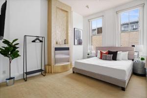 une chambre blanche avec un lit et une plante en pot dans l'établissement Iconic 9BR Landmark in Gaslamp Sleeps 14, à San Diego