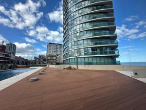 a large building with a wooden deck next to a pool at Clara Suite in Mar del Plata