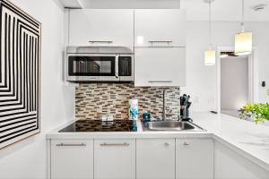 een witte keuken met een magnetron en een spoelbak bij Chic Modern Studio with Queen Bed in Fort Lauderdale