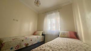 a bedroom with two beds and a window at Cozy Apartment Near Rabat & Beach in Temara