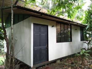 a small house with a black door and windows at Casa la Colmena in Cahuita
