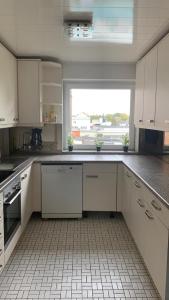 a kitchen with white cabinets and a large window at Lichtdurchflutetes City-Apartment im Herzen der Stadt in Neumünster