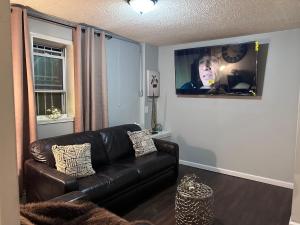 a living room with a leather couch and a flat screen tv at The Layover Lounge in Elizabeth