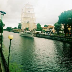 a sail boat is docked in a river at Vilhelm's Apartment in Klaipėda
