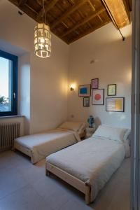 two beds in a bedroom with a chandelier at Appartamento con terrazza La Voliera di Bacco in Frascati