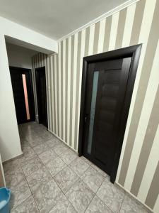 a hallway with two black doors and a tile floor at Apartament 2 camere in Craiova