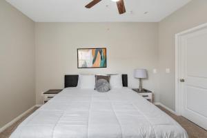 ヒューストンにあるTrendy, upscale apartment!のベッドルーム(大きな白いベッド、天井ファン付)