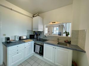 a kitchen with white cabinets and a sink and a counter at Appartement paisible hyper centre in Vichy