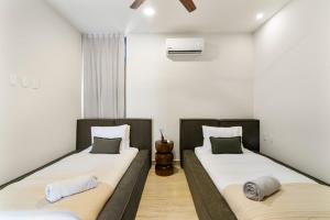 two twin beds in a room with white walls at Luxury Jungle Condos by Casago in Tulum +152 photos