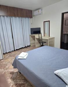 a bedroom with a bed and a desk with a television at Hotel Diplomata in Tupanciretã