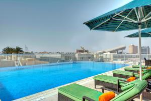 ein Pool mit Stühlen und Sonnenschirmen auf einem Gebäude in der Unterkunft Al Khoory Atrium in Dubai