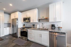 a kitchen with white cabinets and stainless steel appliances at Stylish Grand Lake Retreat - King Bed - Walk to Lake in Grand Lake