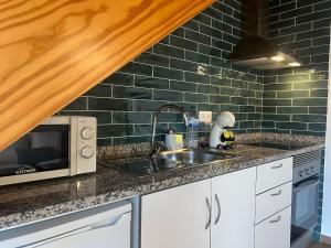a kitchen with a sink and a microwave at Vila Lira in Aljezur