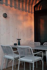 four white chairs and a table with a lamp at Hapfn Tiny House am Aichberg mit Hot Tub und Blick ins Grüne in Eibiswald