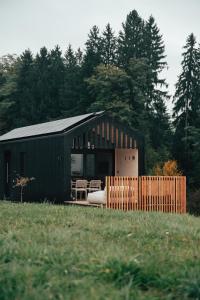 a small black building with a fence in a field at Hapfn Tiny Houses mit Hot Tub in Eibiswald