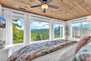 a bedroom with a bed and large windows at Family Chalet With Rooftop Theater GameRoom Mins to DT in Gatlinburg
