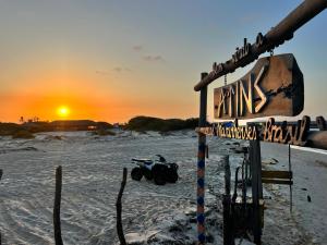 a sign on the beach with the sunset in the background at chale vilana in Atins