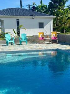 three chairs and a house with a swimming pool at Mango-passion Le Domaine Mannou in Sainte-Rose