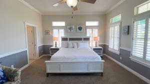 Un dormitorio con una cama blanca y un ventilador de techo. en Luxury 1 min to Beach Pool New Remodel, en South Padre Island