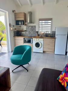 a kitchen with a green chair and a refrigerator at Mango-passion Le Domaine Mannou in Sainte-Rose