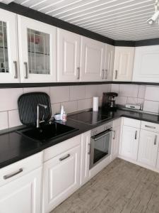 a kitchen with white cabinets and black counter tops at Käpt'n Brandt in Osteel