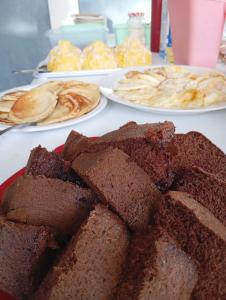 BarroquinhaにあるPousada Paraíso das Dunasのブラウニーやその他の食べ物の皿が置かれたテーブル