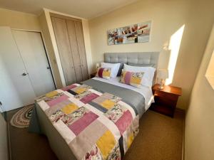 a bedroom with a bed with a quilt on it at Departamento Mirador Camilo Henriquez in Concepción