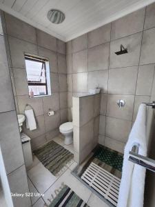 a bathroom with a shower with a toilet and a window at 87 on Sunbird B in Langebaan