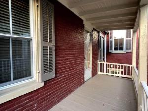 a porch of a red brick house with a window at THE ADDAMS HOUSE - LANCASTER HISTORIC DISTRICT in Lancaster