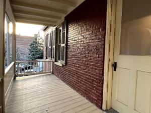 a porch with a brick wall and a white door at THE ADDAMS HOUSE - LANCASTER HISTORIC DISTRICT in Lancaster