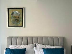 a wall with a picture above a bed with blue pillows at Bellísima Suite, 2 Camas Queen, Gym, en Interlomas in Mexico City