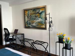 墨西哥城Bellísima Suite, 2 Camas Queen, Gym, en Interlomas的一间卧室，里面有一张书桌、几把椅子和一幅画。