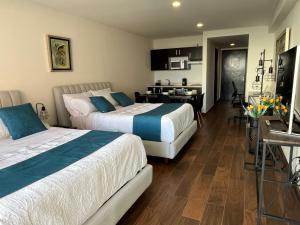 a hotel room with two beds and a kitchen at Bellísima Suite, 2 Camas Queen, Gym, en Interlomas in Mexico City