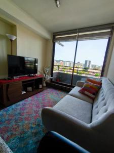 a living room with a couch and a large window at Departamento Mirador Camilo Henriquez in Concepción