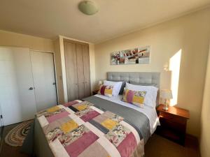 a bedroom with a bed with a quilt on it at Departamento Mirador Camilo Henriquez in Concepción