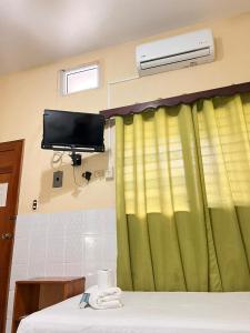 a room with a green curtain and a tv and a bed at Hotel Hernandez in Chiquimula
