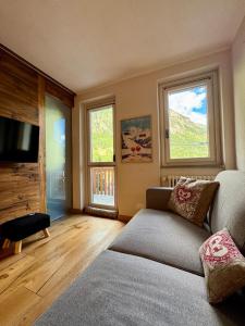 a living room with a couch and two windows at Nido Alpino - Vista Montagne, Ski e Relax Terme a 150m in Pré-Saint-Didier
