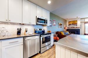 スティームボート・スプリングズにあるSki Time Square 301の白いキャビネットとコンロ付きオーブンを備えたキッチン