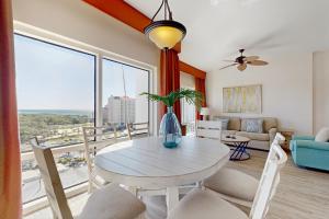 Una sala de estar con una mesa y sillas y una gran ventana. en Luau 6909, en Destin