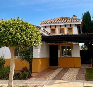 a yellow and white house with a tree at Villa Alegre - 2 bed villa with private heated pool on Mar Menor Golf - family friendly in Torre-Pacheco