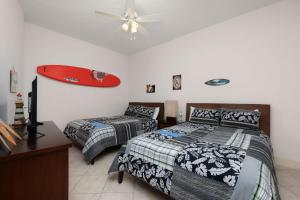 a bedroom with two beds and a surfboard on the wall at Prestigious Luxury Beach & Bay Patios XL Size in South Padre Island