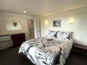 a bedroom with a bed and a clock on the wall at Abri Apartments in Paihia